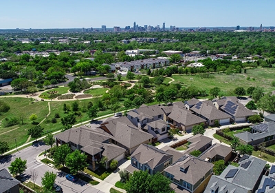 Overhead view of houses with solar panels on rooftops and downtown buildings in background
